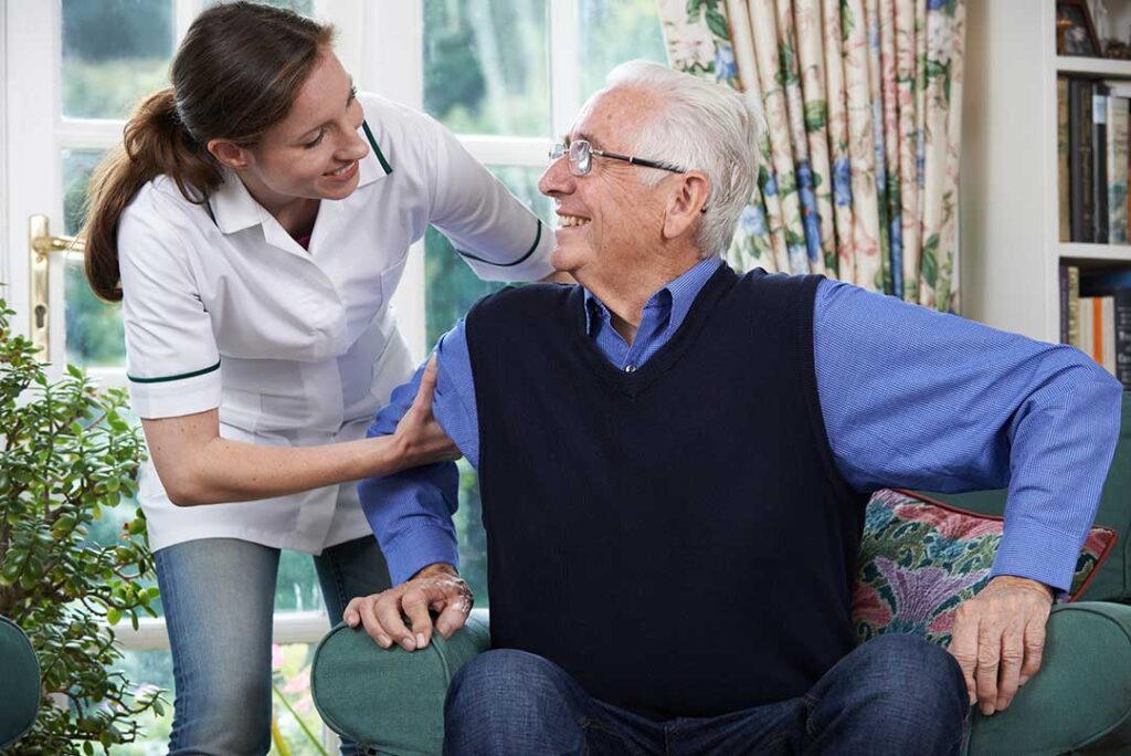 Caregivers assisting several older adults with daily activities in a communal assisted living space.